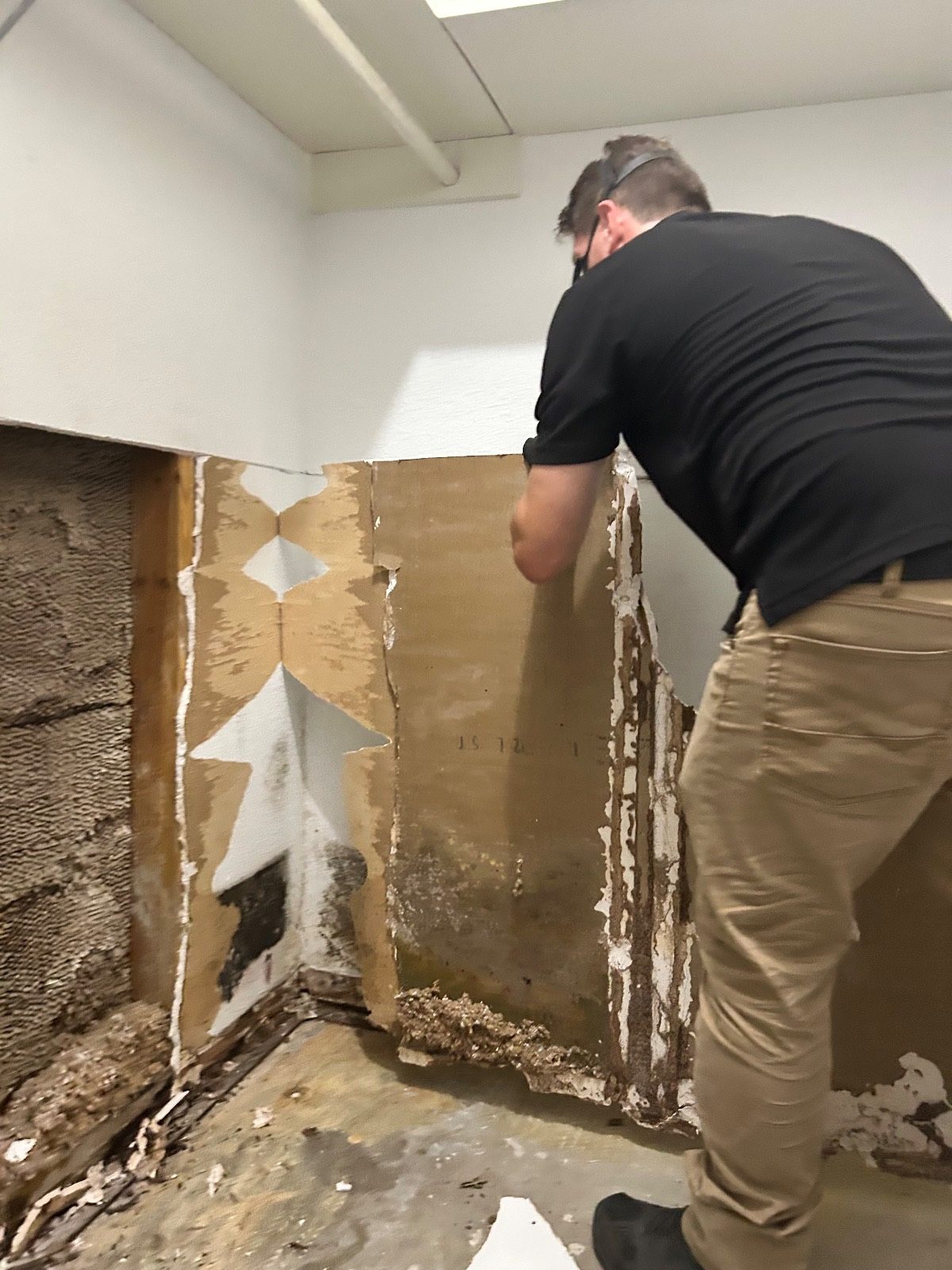 Technician cutting damaged wallboard out of a corner of a room