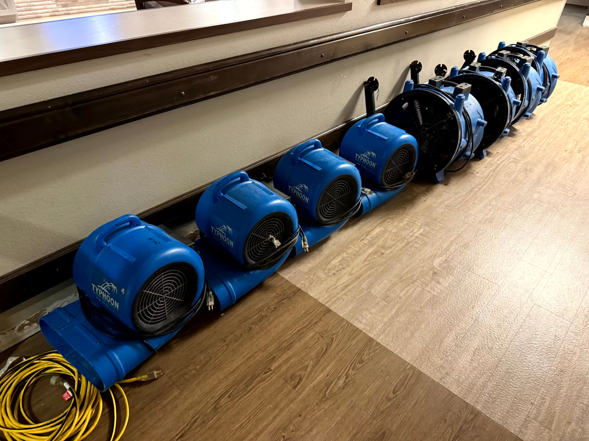 Row of commercial air movers drying a corridor during structural drying