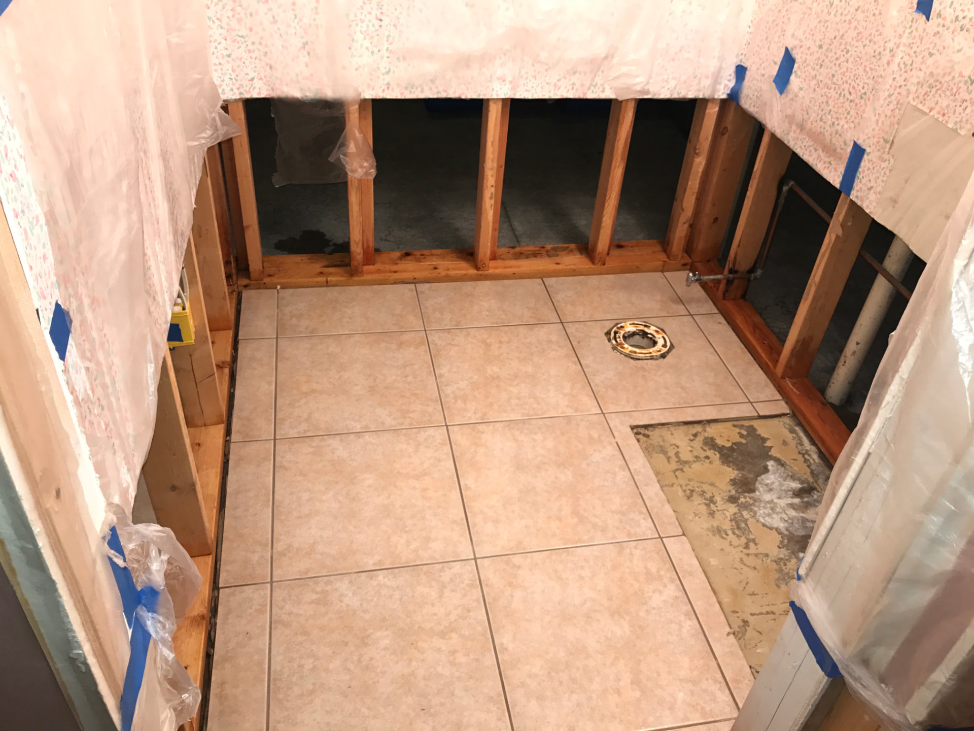 Bathroom gutted to the studs under plastic containment during contaminated water cleanup