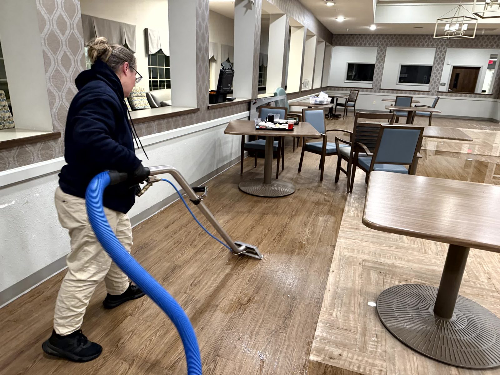 Technician pulling water from a hallway floor with an extraction wand